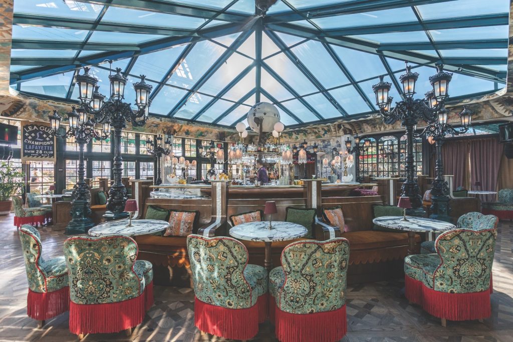 Consortium Holding's newly renovated Lafayette Hotel in North Park, San Diego featuring their lobby bar with lamps, decorative chairs, and a large skylight 